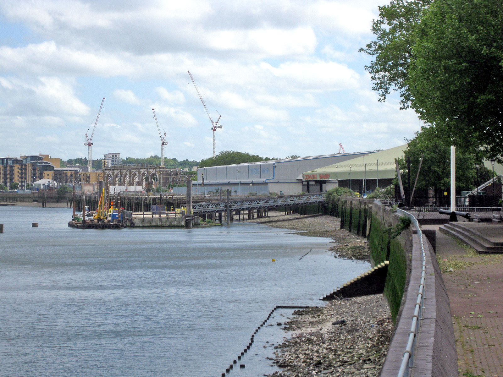 Convoys Wharf, Deptford, seen from the Thames Path at low tide, cranes on the skyline